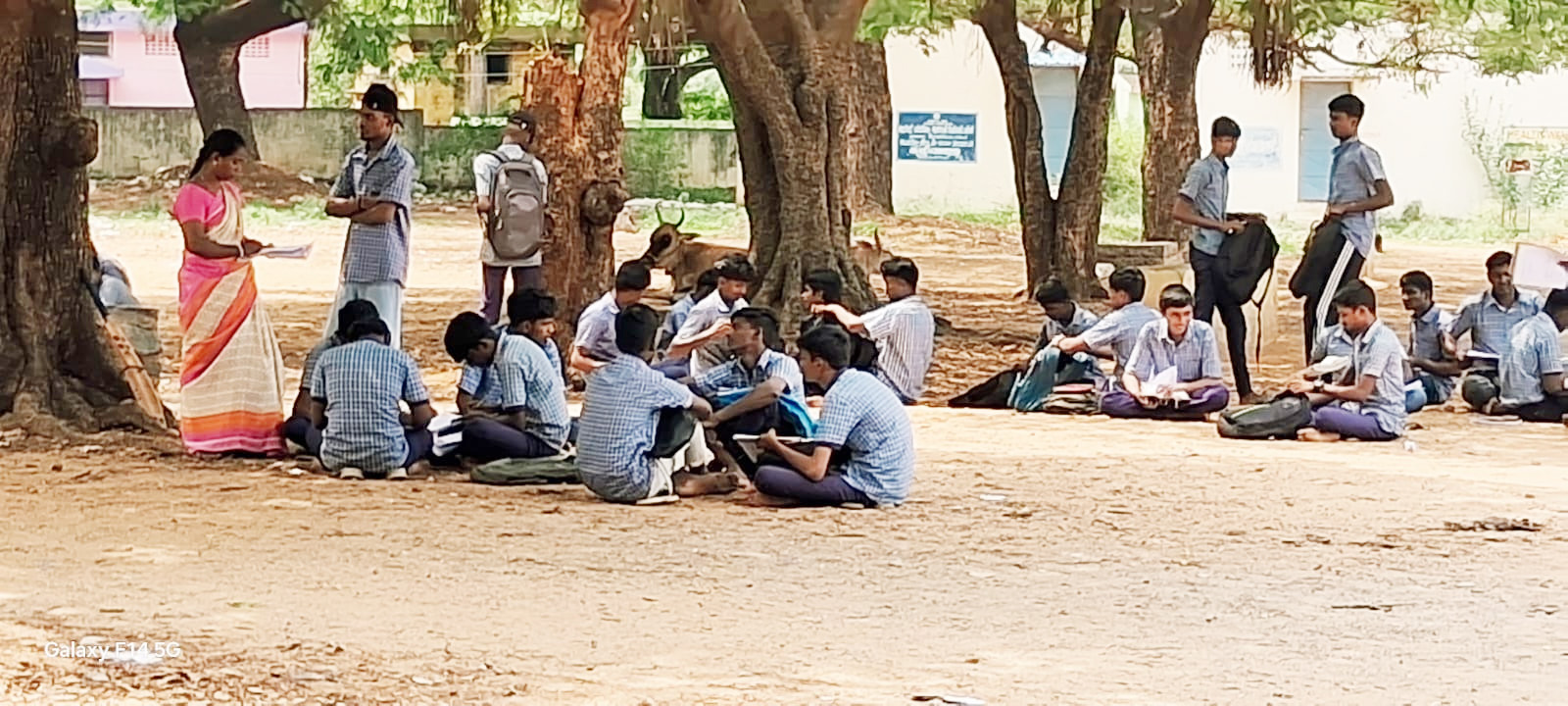 வாலாஜாபேட்டை பள்ளி வளாகத்தில் தரையில் அமர்ந்து படிக்கும் மாணவர்கள்